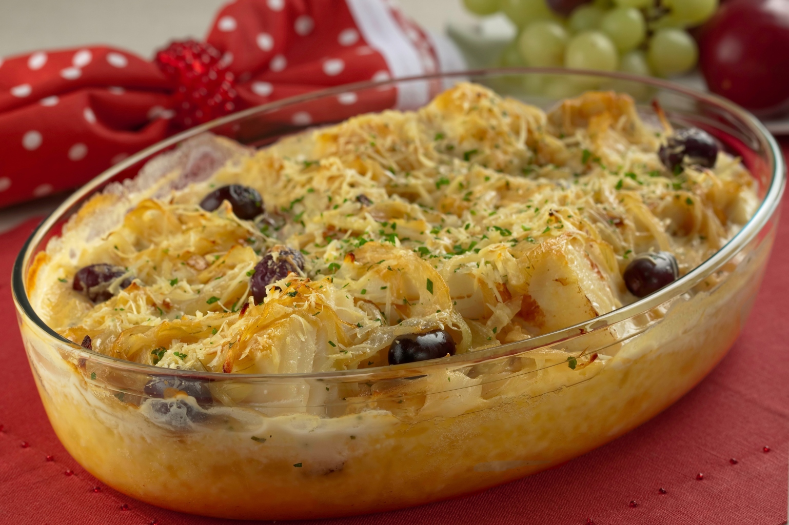 Foto de bacalhau gratinado com creme de mandioca em uma travessa.