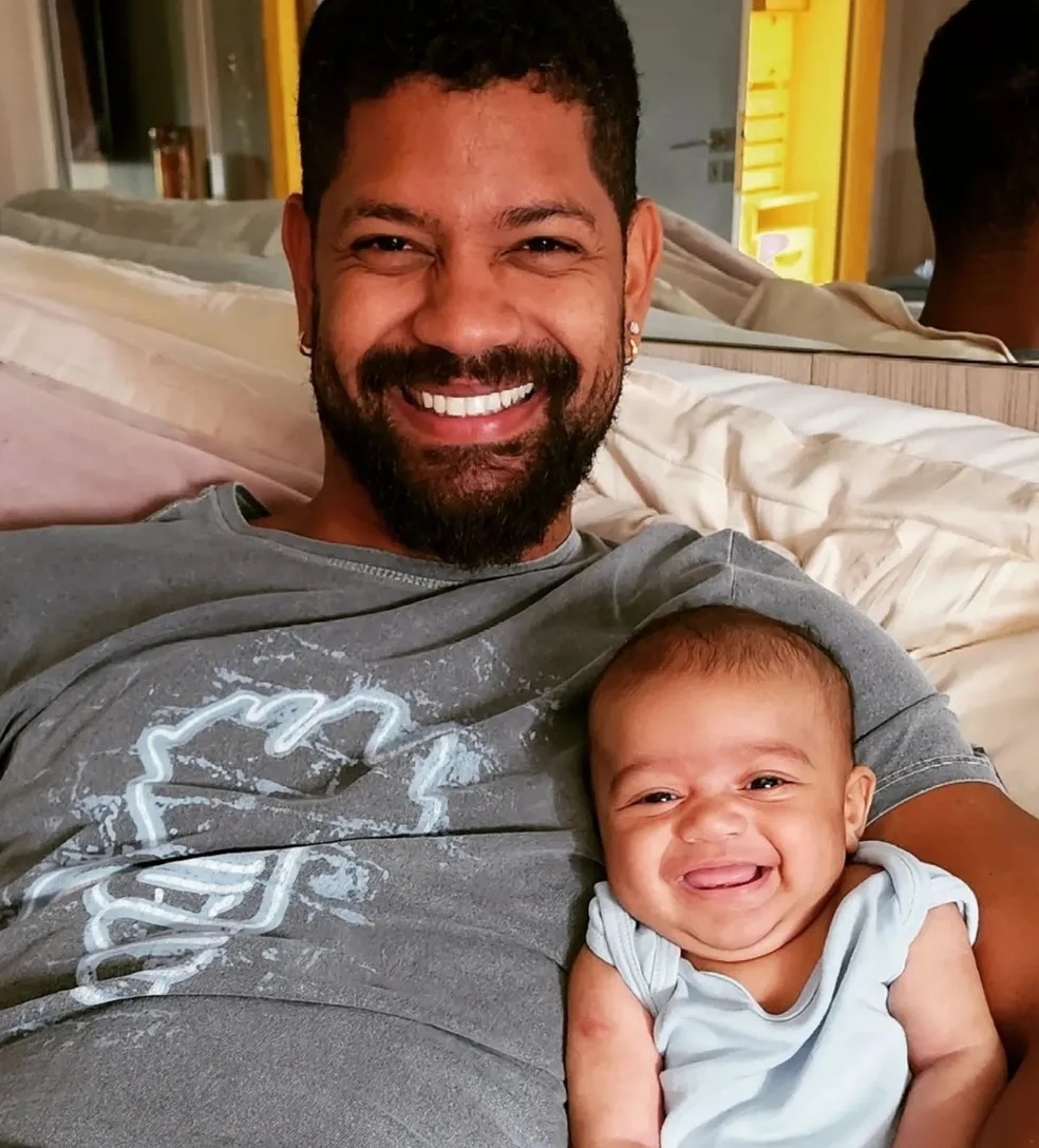 Foto de Joaquim no colo de Guilherme Militão, filho e marido de Viviane Araujo, respectivamente