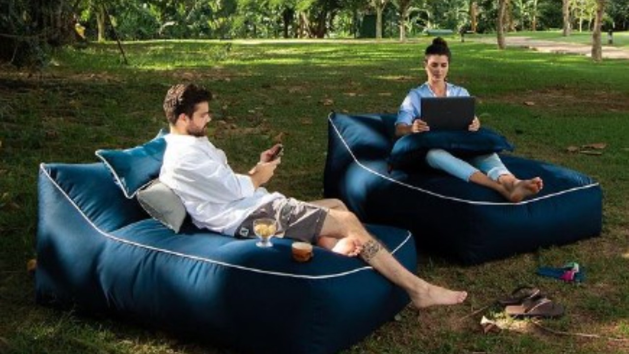 Duas pessoas sentadas em pufes separados em um jardim cheio de natureza