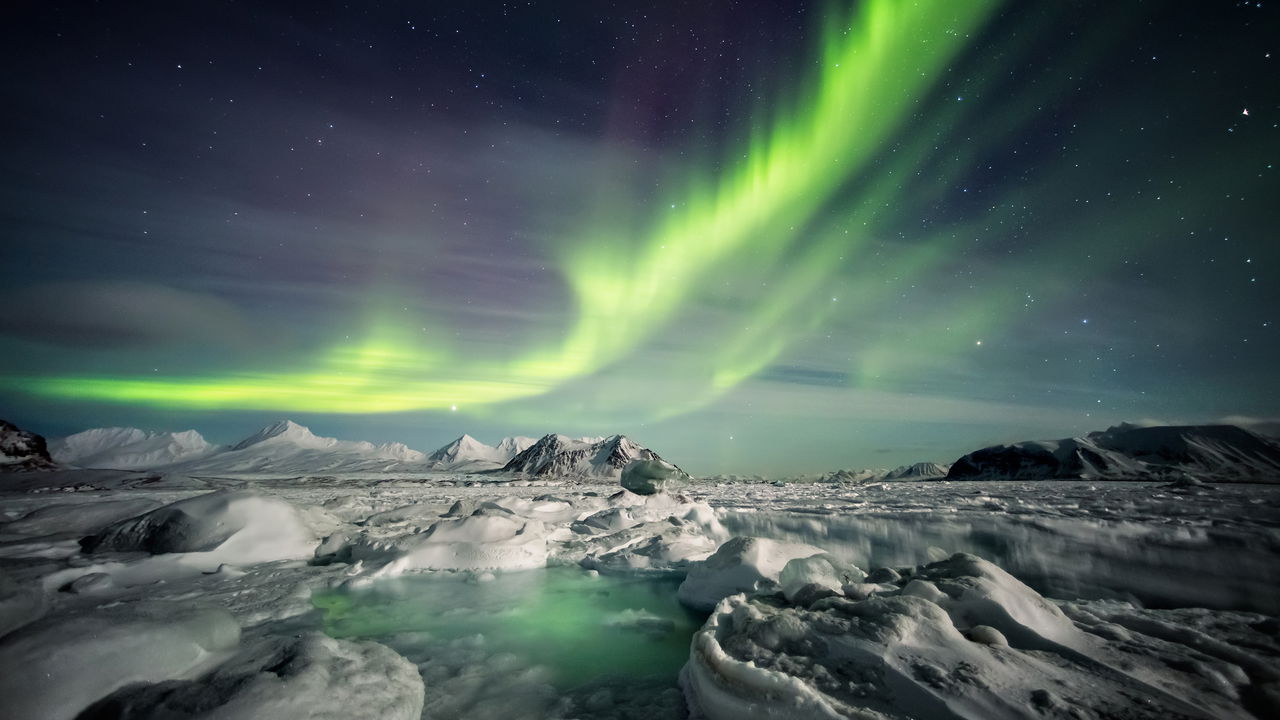 Paisagem incomum de inverno ártico - Fiorde congelado e auroras boreais