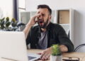 Homem trabalhando com sono - Créditos: depositphotos.com / SarkisSeysian