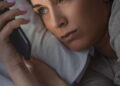 Ilustração de mulher mexendo no celular antes de dormir - Créditos: depositphotos.com / HayDmitriy