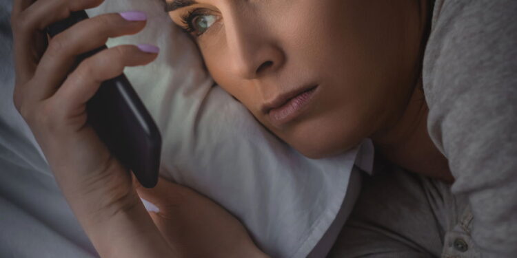 Ilustração de mulher mexendo no celular antes de dormir - Créditos: depositphotos.com / HayDmitriy