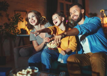 Família assistindo feliz a série viciante - Créditos: depositphotos.com / evgenyataman