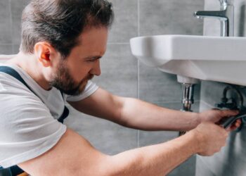 A principal origem do mau cheiro no ralo do banheiro é o acúmulo de resíduos orgânicos, como fios de cabelo, restos de sabonete e gordura corporal, que se depositam na tubulação. Com o tempo, esse material entra em decomposição e libera gases desagradáveis, que retornam ao ambiente quando não há vedação adequada. Quais sinais indicam que o problema vai além da limpeza? Um sinal claro de que o problema vai além da limpeza superficial é quando o cheiro retorna poucas horas ou dias depois da higienização. Isso indica que o foco do mau odor está mais profundo na tubulação ou relacionado ao sistema hidráulico do imóvel. Outro indício importante é quando o odor se intensifica após o uso de outros pontos de água da casa. Esse comportamento pode estar ligado a falhas de ventilação do encanamento, o que facilita o retorno dos gases do esgoto pelo ralo do banheiro. Como eliminar o cheiro do ralo do banheiro com soluções caseiras? Entre as formas mais eficazes de como eliminar o cheiro do ralo do banheiro, as soluções caseiras funcionam bem quando aplicadas corretamente. A combinação de bicarbonato de sódio e vinagre promove uma reação que ajuda a soltar resíduos presos nas paredes do cano. O procedimento é simples e seguro para a tubulação quando feito com moderação. Após despejar os ingredientes, a finalização com água quente auxilia na remoção da gordura acumulada, reduzindo o odor e prevenindo novos entupimentos. Quando o sifão é o verdadeiro causador do mau cheiro? O sifão é responsável por criar uma barreira de água que impede a passagem dos gases do esgoto. Quando essa peça está seca, rachada ou mal instalada, o cheiro surge mesmo que o ralo esteja limpo. Em banheiros pouco utilizados, a água do sifão pode evaporar, quebrando essa barreira natural. Nesses casos, jogar água no ralo semanalmente ou substituir sifões antigos por modelos rígidos melhora significativamente a vedação contra odores. Quais erros comuns agravam o cheiro no ralo? Um erro frequente é o uso excessivo de produtos químicos agressivos, como soda cáustica. Apesar de populares, essas substâncias podem danificar a tubulação, corroer conexões e agravar o problema a médio prazo. Outro equívoco é tentar apenas mascarar o cheiro com produtos perfumados. Essa prática não elimina a causa e cria uma falsa sensação de limpeza, enquanto o foco correto deve ser sempre a remoção da origem do mau odor. Como a ventilação do banheiro influencia o mau cheiro? A ventilação tem papel direto na percepção e concentração dos odores. Banheiros sem janelas ou com circulação de ar insuficiente tendem a reter os gases vindos do ralo por mais tempo. Ambientes bem ventilados reduzem a umidade, dificultam a proliferação de bactérias e ajudam a dispersar odores residuais. Sempre que possível, manter janelas abertas ou utilizar exaustores melhora significativamente a qualidade do ar. Quais hábitos evitam que o cheiro volte a aparecer? A prevenção é a forma mais eficiente de manter o ralo sem odor. Pequenos hábitos no dia a dia reduzem drasticamente o risco de novos episódios. Entre as práticas mais recomendadas estão: Não descartar cabelos e resíduos sólidos no ralo Fazer limpeza preventiva a cada quinze dias Manter o sifão sempre com água Verificar periodicamente folgas ou vazamentos Essas ações simples mantêm a tubulação funcional e evitam o retorno do mau cheiro. O que podemos aprender sobre como eliminar o cheiro do ralo do banheiro? Entender como eliminar o cheiro do ralo do banheiro mostra que o problema raramente está ligado a algo complexo. Na maioria dos casos, ele surge por falta de manutenção básica e hábitos inadequados. Ao transformar a prevenção em rotina, o banheiro se torna mais higiênico, confortável e livre de odores persistentes. A escolha final é simples: lidar com o cheiro quando ele aparece ou evitar que ele volte a surgir.